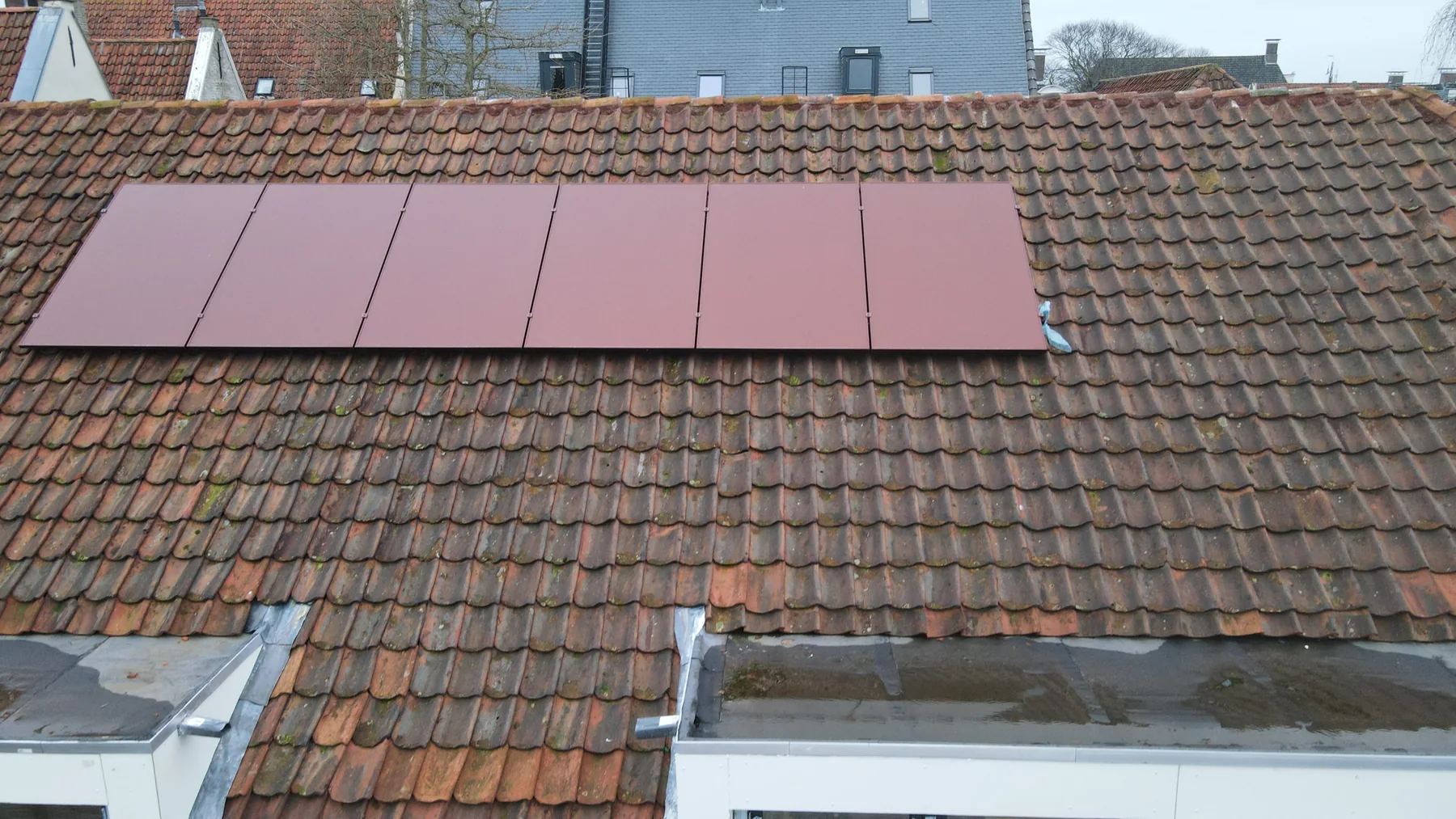 Detail van rode zonnepanelen op een bestaand rood pannendak