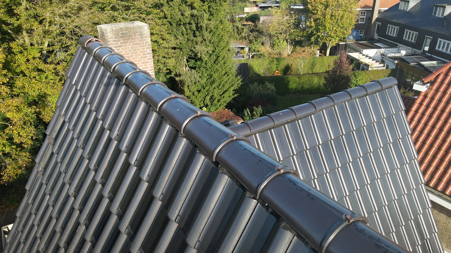 Detail van zwarte zonnedakpannen bij de nok en aansluitende dakvlakken